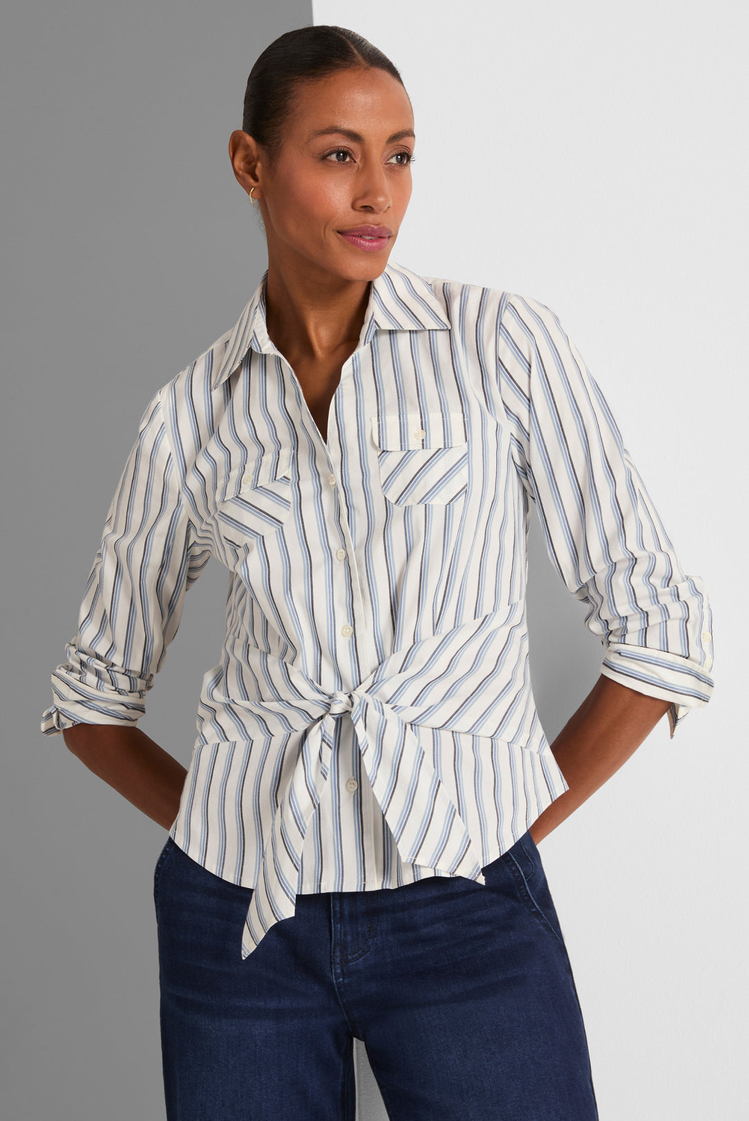 Woman wearing a striped shirt and jeans against a gray background