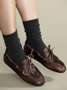 Charcoal gray ribbed socks, scrunched above dark brown shoes.