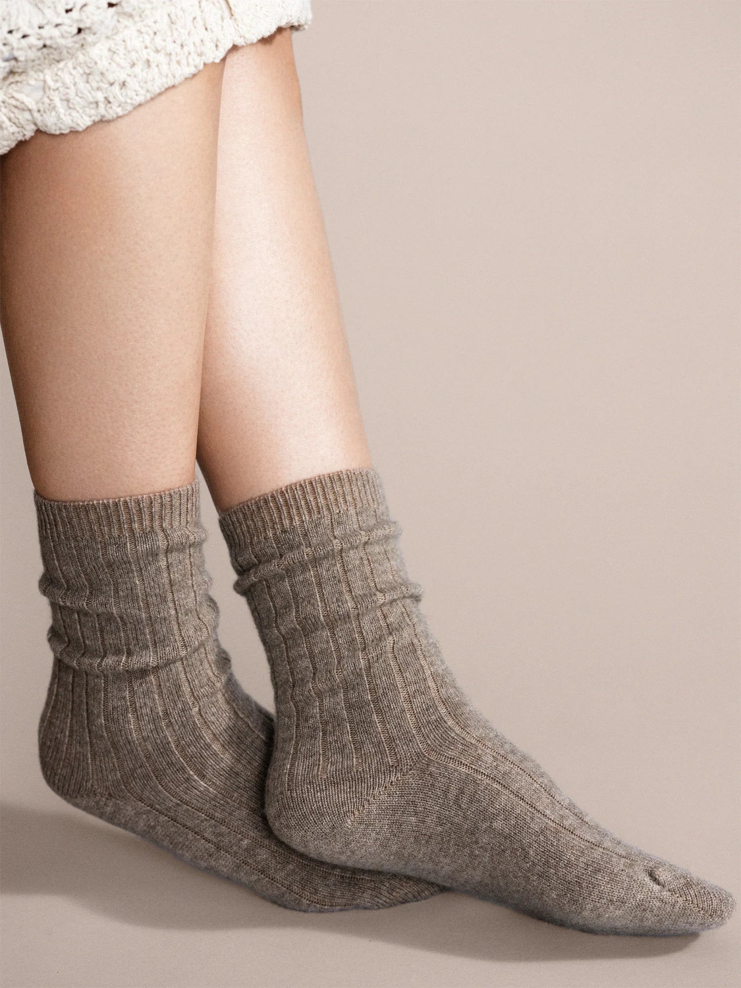 Grayish-brown, ribbed cashmere socks on feet. Crew length, slightly bunched.