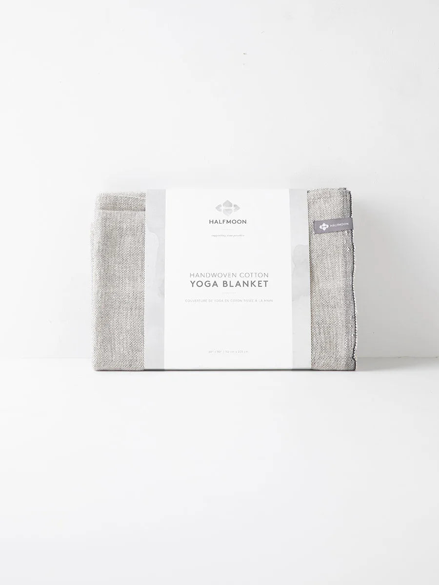 Folded natural woven yoga blanket with a white product label wrapped around it.