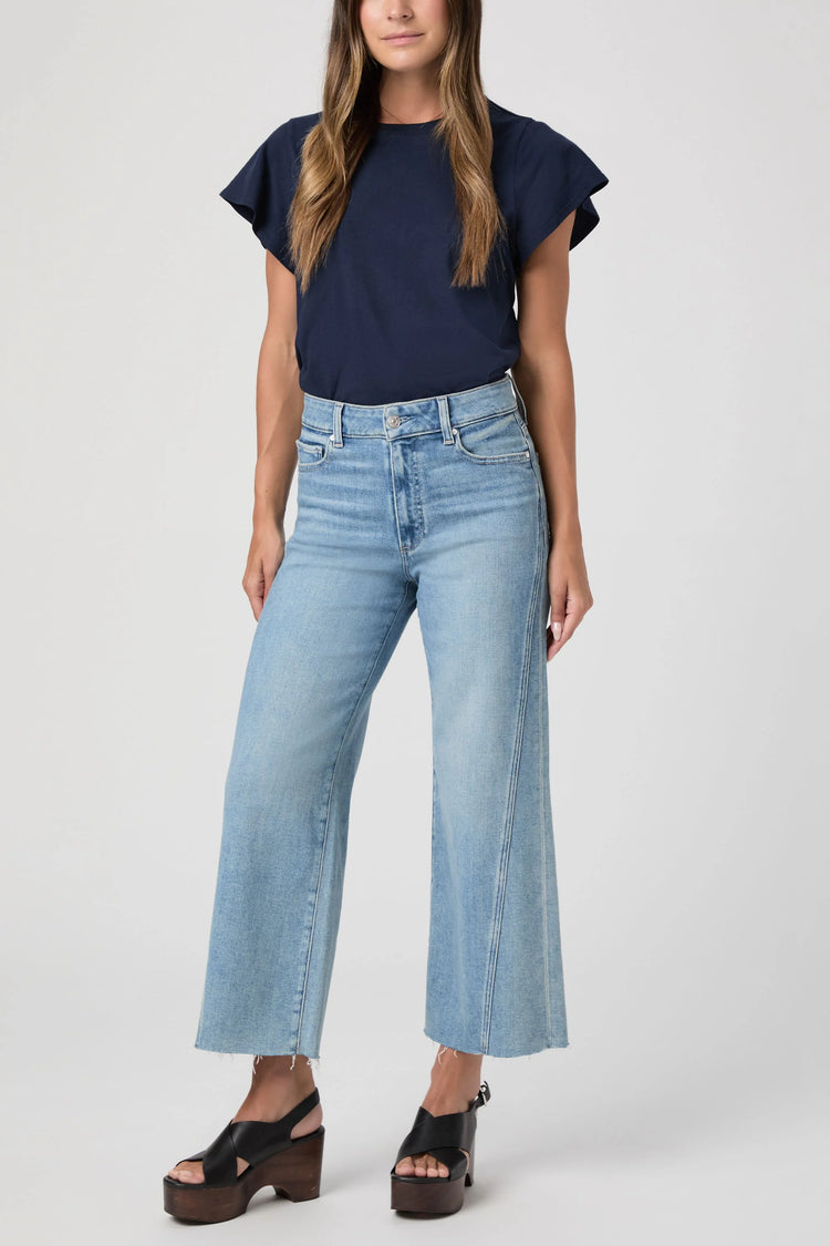 Light blue high-waist wide-leg jeans with twisted outseam panels and a frayed cropped hem.
