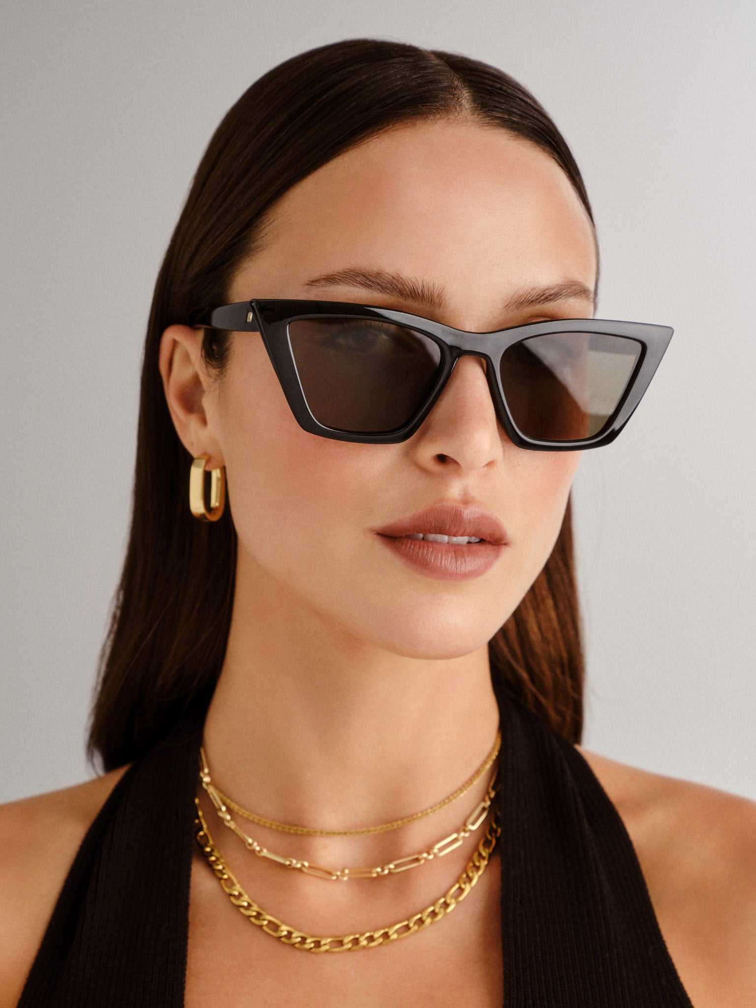 A model wears chic black cat eye sunglasses with bold angular frames and dark lenses for a sophisticated look.