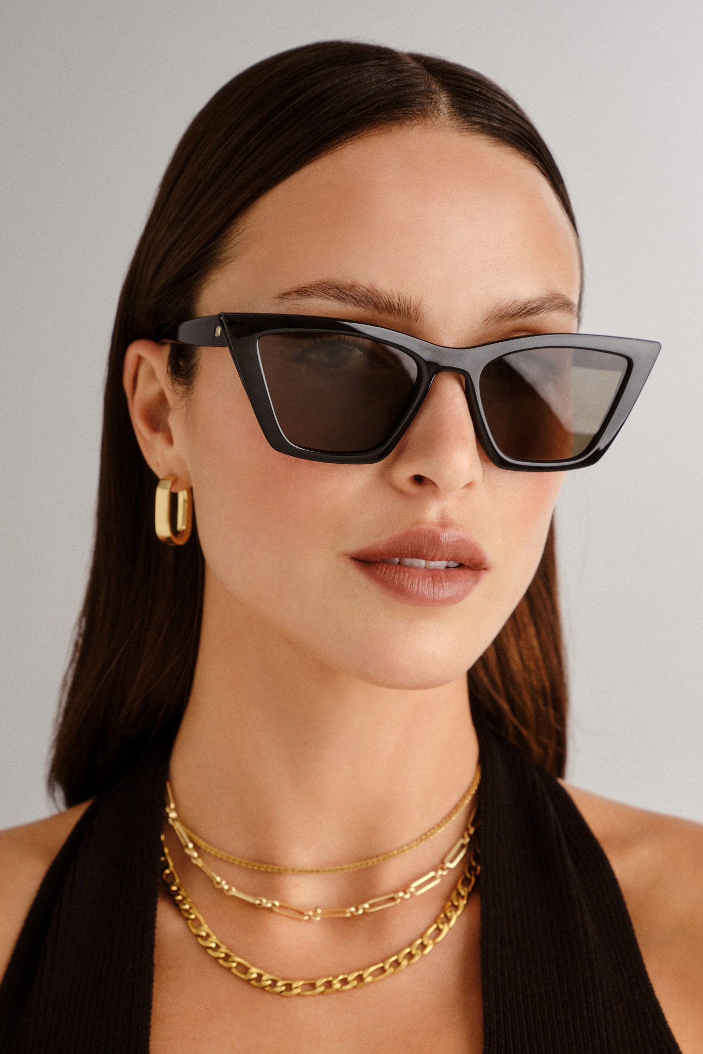 A model wears chic black cat eye sunglasses with bold angular frames and dark lenses for a sophisticated look.