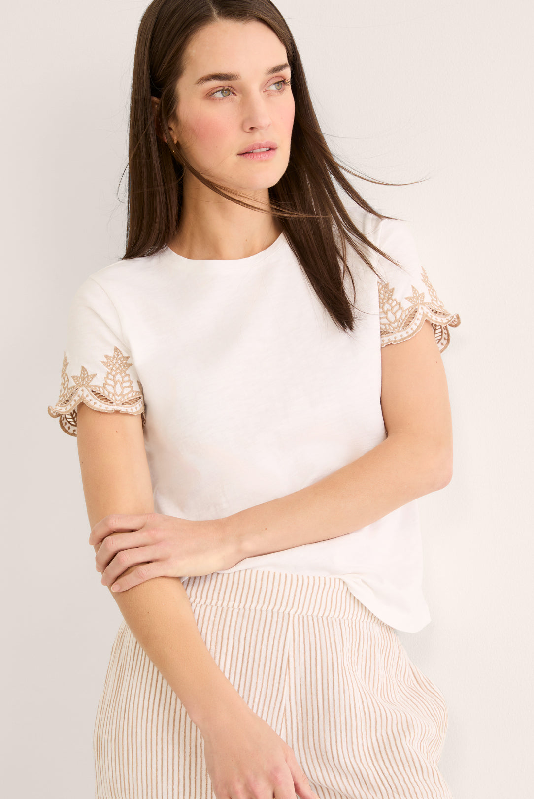 Woman wearing a white blouse with lace sleeves against a plain background