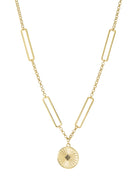 Gold chain necklace with rectangular bar links. Round disc pendant features radial lines and a black square stone cluster.