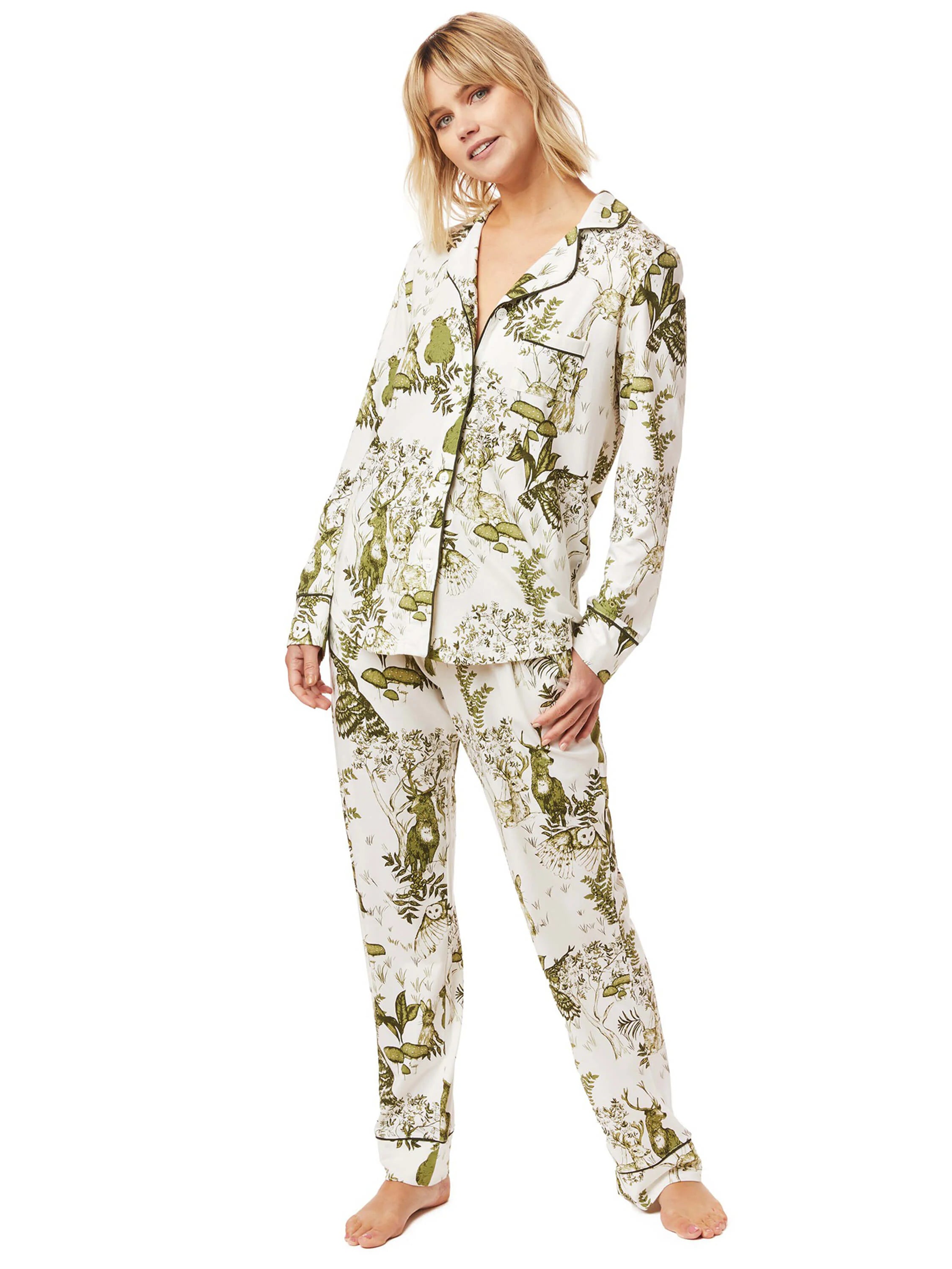 Cream pajama set with a green forest animal and foliage print. Features black piping on the collar, cuffs, and hems.