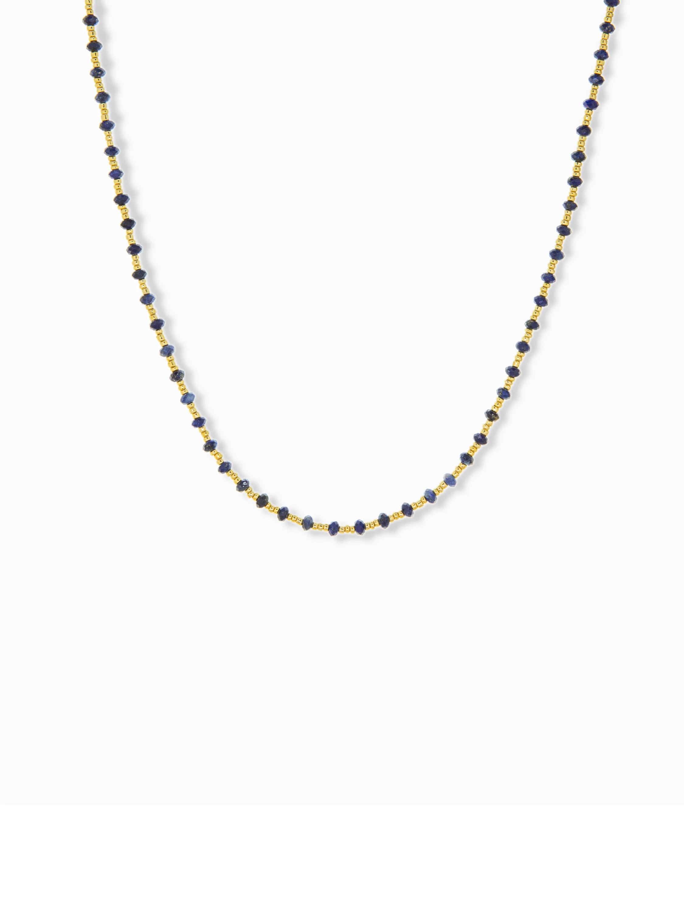 Gold chain necklace with small, dark-blue beads.