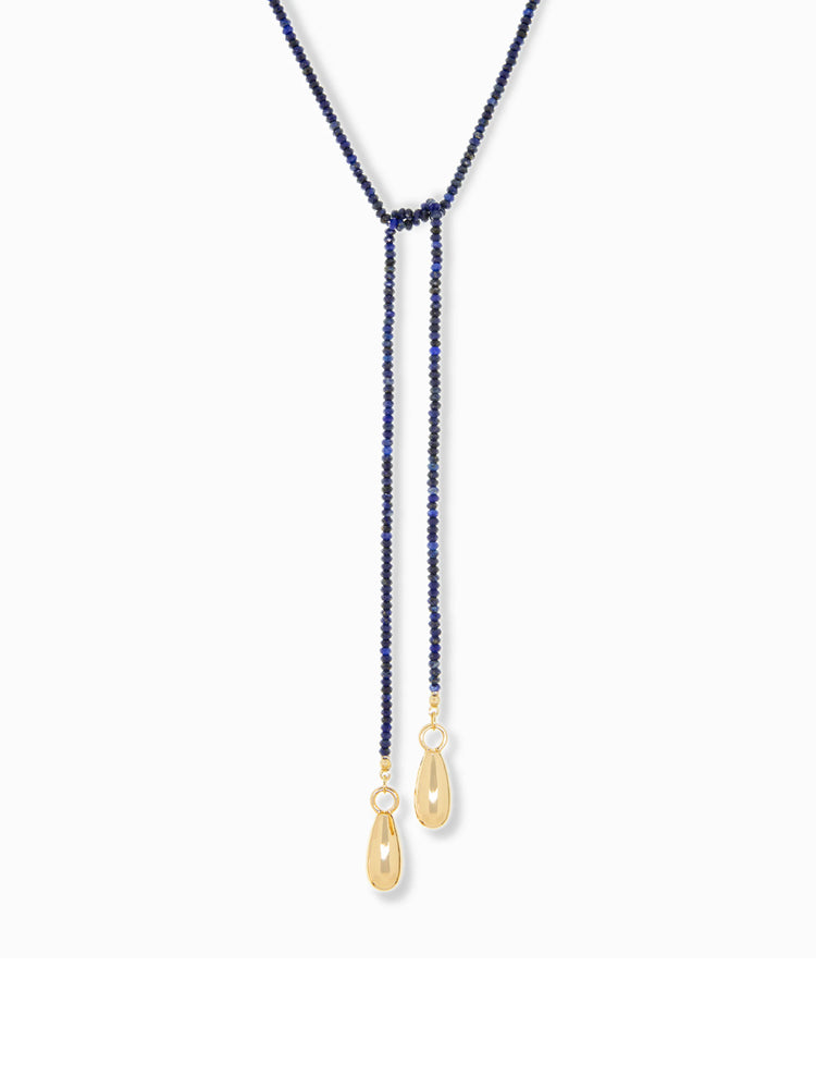 Blue beaded lariat necklace with gold teardrop charms. The lariat has a knotted center.