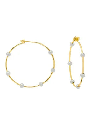 Gold-tone hoop earrings with several evenly spaced white beaded balls. One earring appears larger.