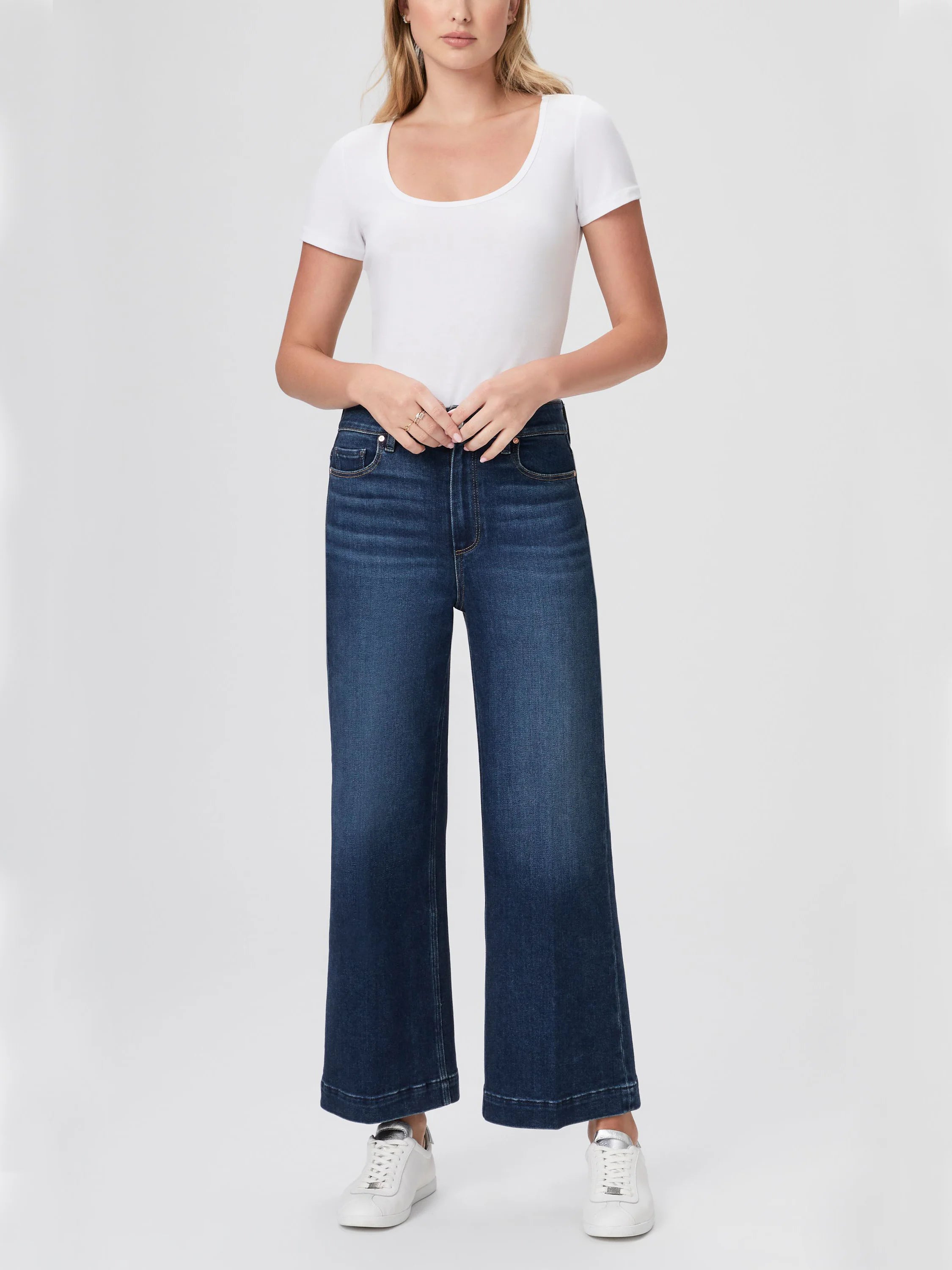 Dark wash, wide-leg jeans; model wears white top & sneakers.