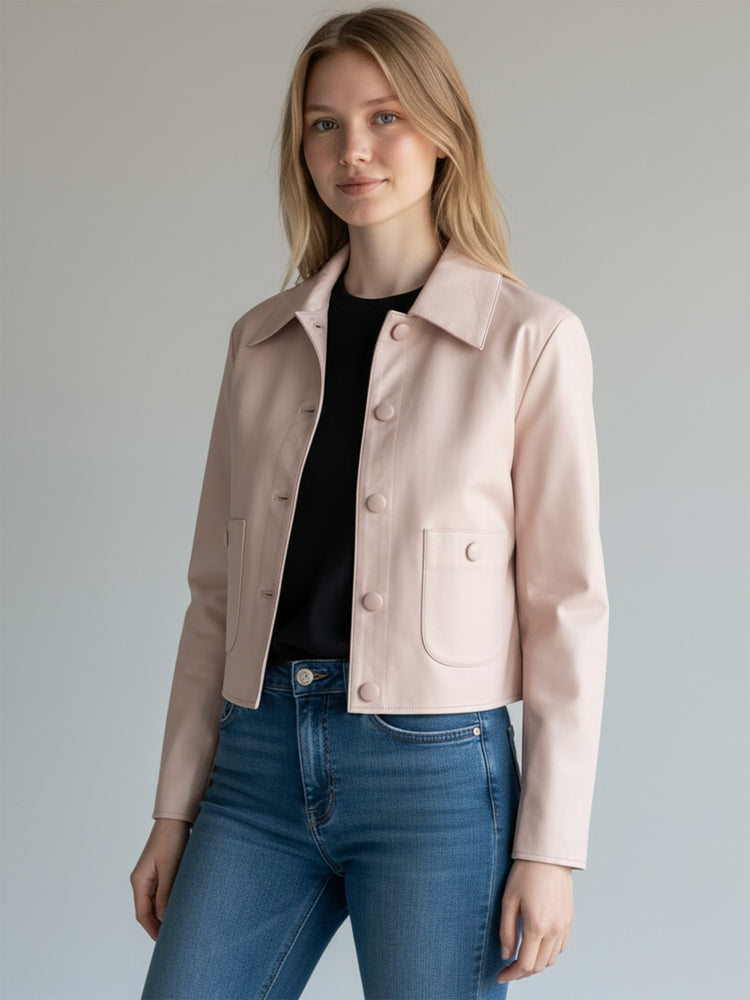 A model wears a cropped blush pink faux leather jacket featuring large buttons and front patch pockets.