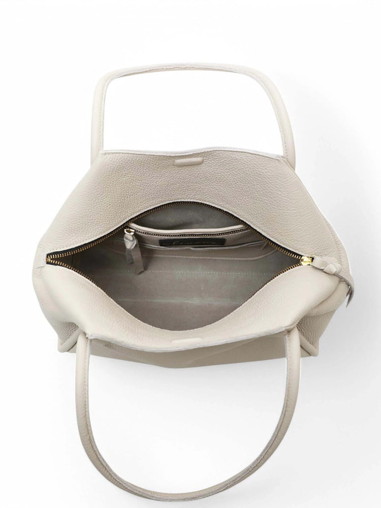 Beige tote bag with top zipper, two handles, and an interior pocket. Gold zipper pull. Inside is light beige.