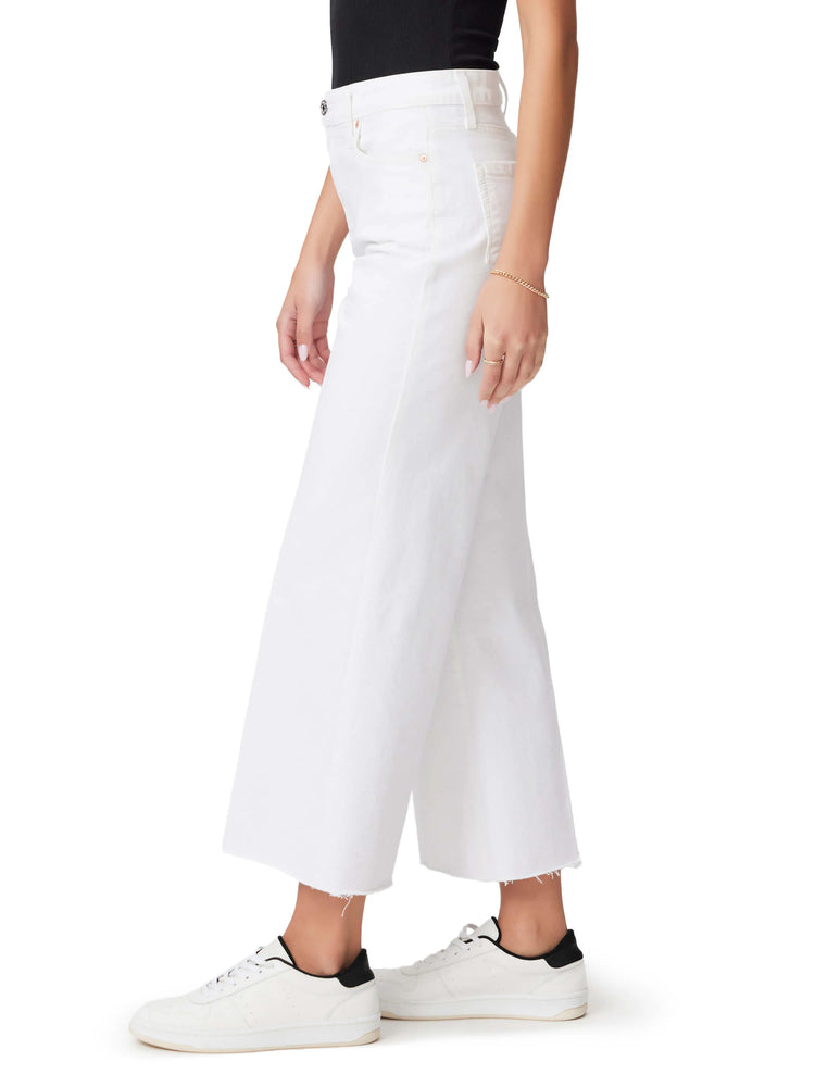 White wide-leg jeans with raw hem. Model wears white sneakers.