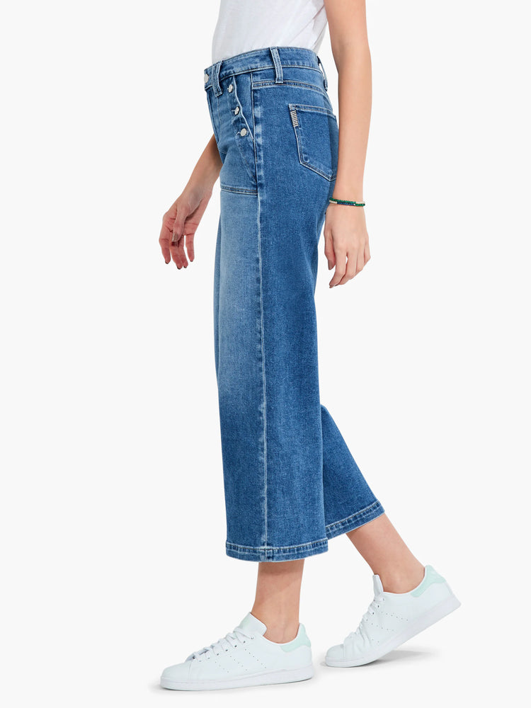 Medium-wash blue, wide-leg cropped jeans; button fly. Model wears white sneakers.