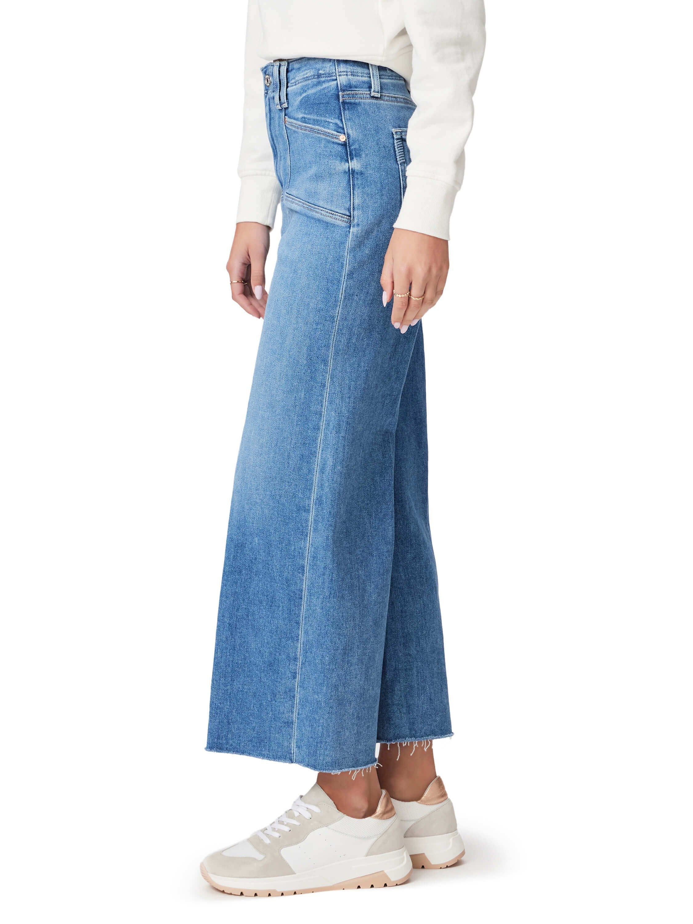 Light wash blue, wide-leg jeans with frayed hem; shown on model wearing off-white sneakers.