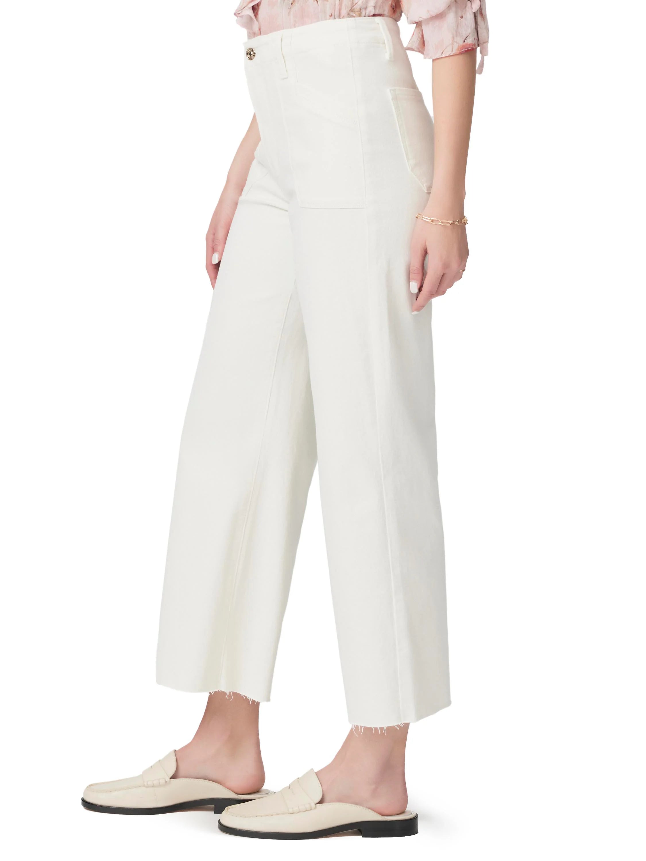 Off-white wide-leg pants with raw hem, utility pockets, and gold button. Shown on a model.