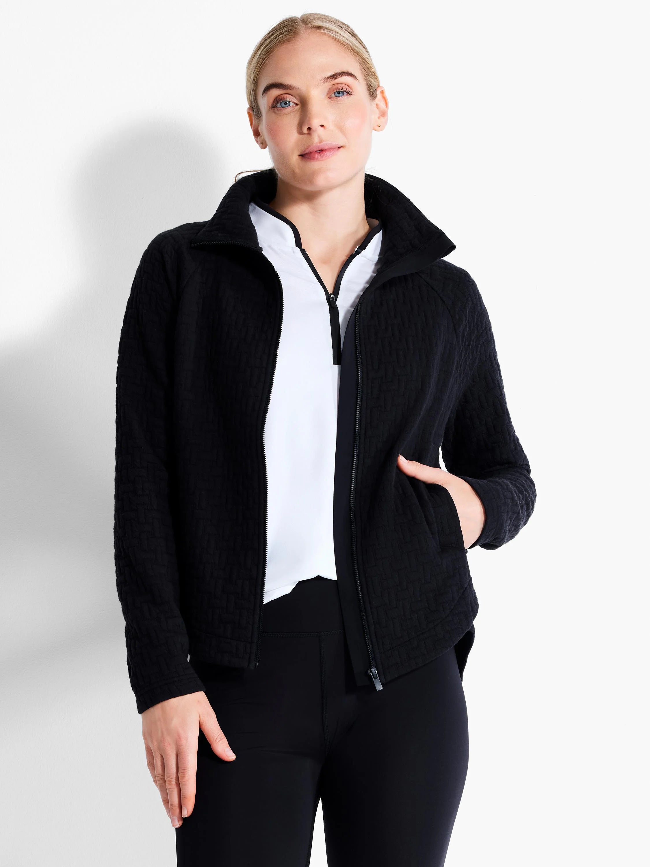 Black quilted jacket with a subtle geometric texture, full front zipper, and a standing collar. Model wears it over a...