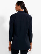 Black long-sleeved collared shirt, relaxed fit, tunic length, visible from behind. Features a horizontal back yoke seam.