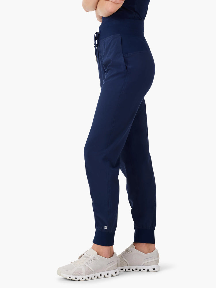 Dark navy high-waisted joggers with a wide, elasticated waistband, drawstring, side pocket, tapered legs, and ankle cuffs.