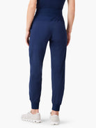 Navy blue high-waisted jogger pants with a wide waistband and elastic ankle cuffs, shown from the back on a person.