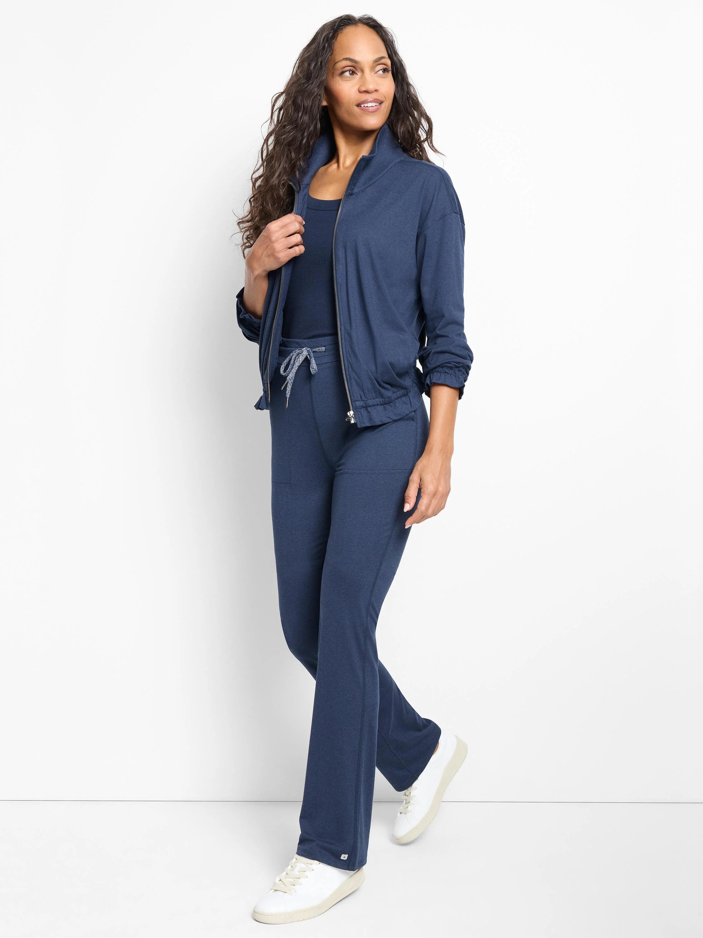 Navy blue zip-front jacket, cuffed sleeves, and matching pants. Model wears white sneakers.