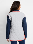 Reversible coat: quilted light gray body, navy blue sleeves, with coral trim on collar, cuffs, and hem.