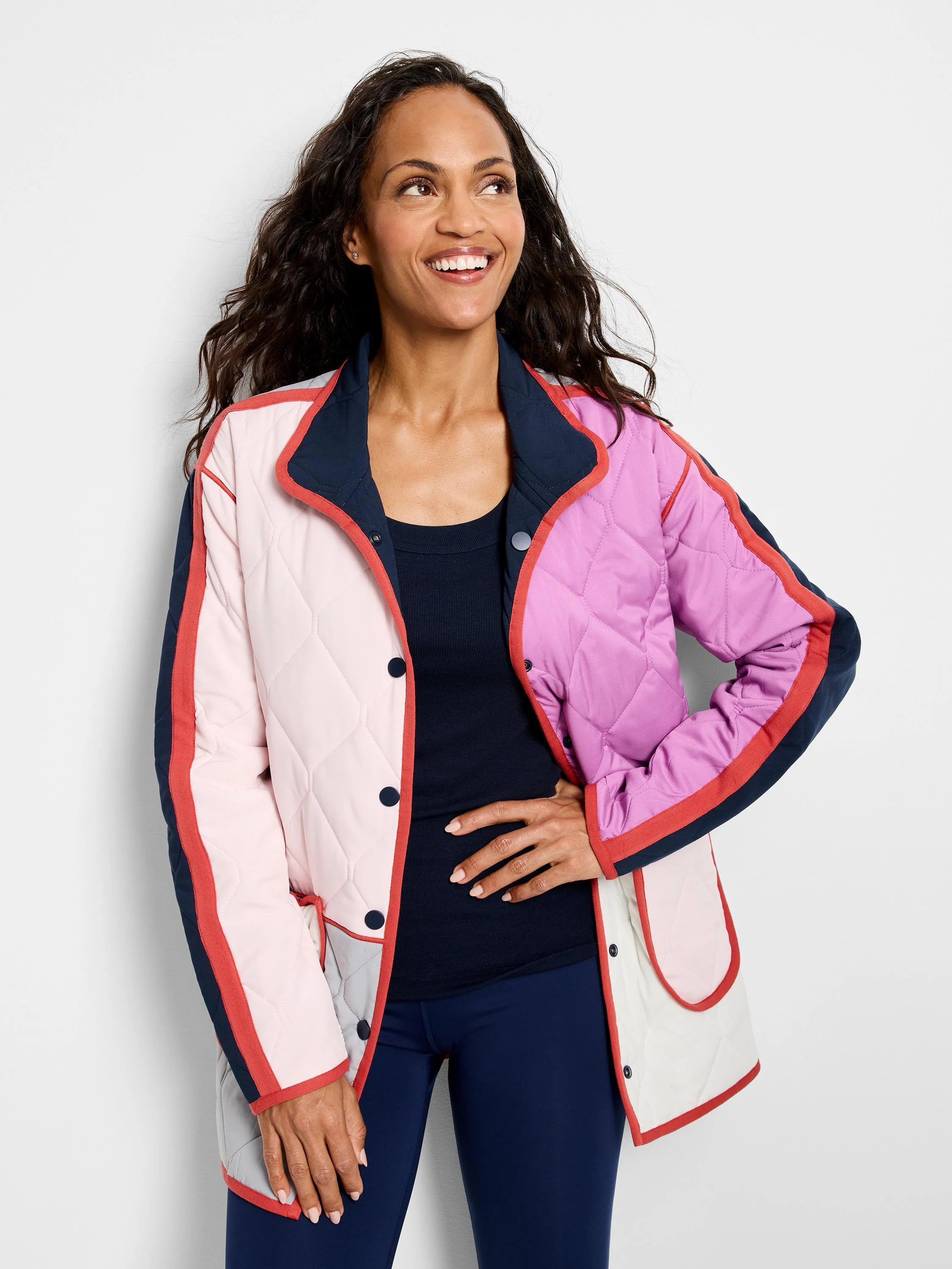 Quilted coat: geometric color blocks in light pink, mauve, grey, and navy. Accented with orange-red trim and navy snaps.
