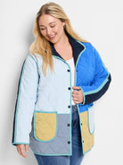 Quilted coat in color blocks of pale blue, royal blue, navy, pale yellow, and gray-blue with aqua trim, dark buttons.