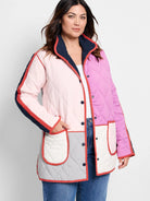 Quilted coat in pink, magenta, grey, and white color blocks. Features red piping, navy collar, and navy sleeve stripes.
