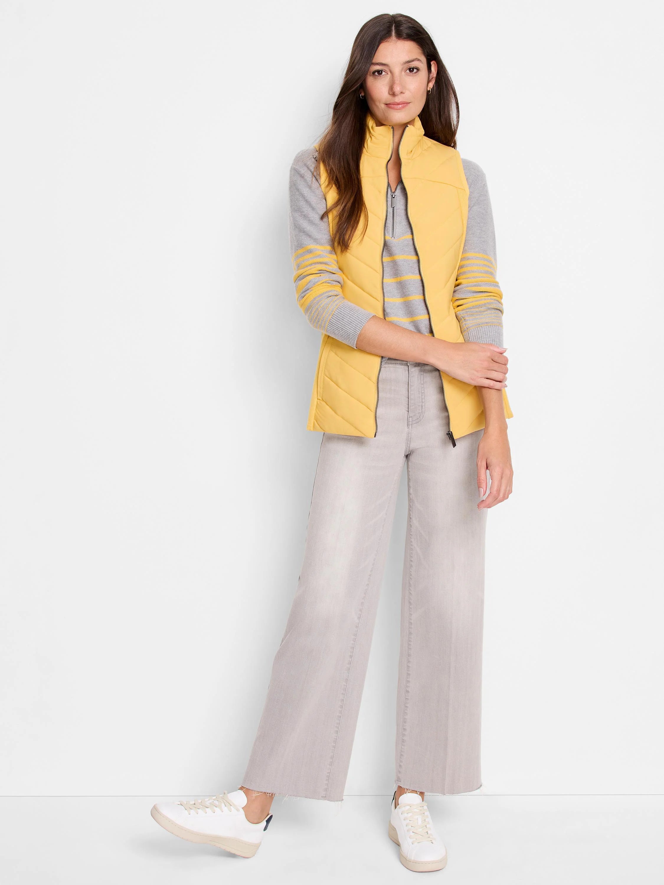 Mustard yellow quilted half-zip vest. Model also wears grey striped sweater and light grey pants.