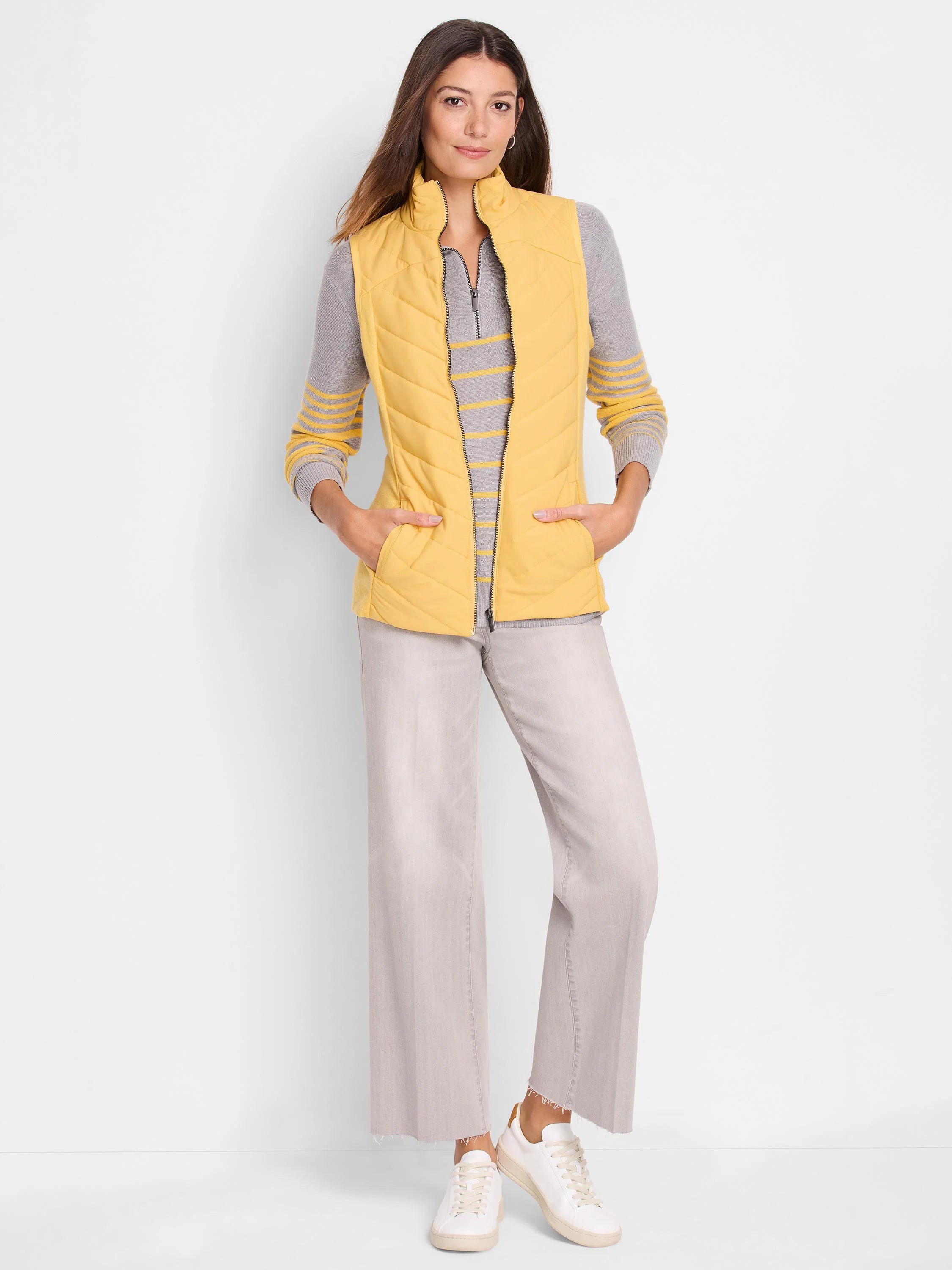 Mustard yellow quilted puffer vest with zipper and pockets. Shown with gray striped top and light gray pants.