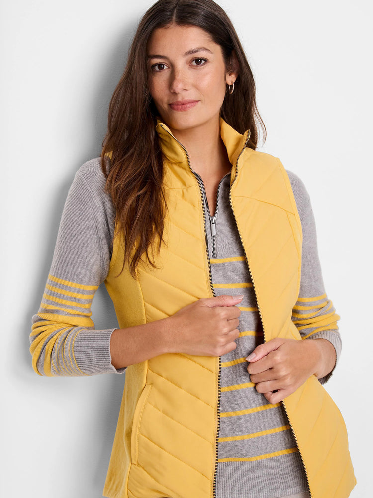 Mustard yellow quilted puffer vest with a zipper. Gray and yellow striped knit top underneath.