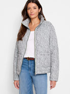 Light gray quilted puffer jacket with dark gray abstract dash pattern, green zipper trim, and stand-up collar.