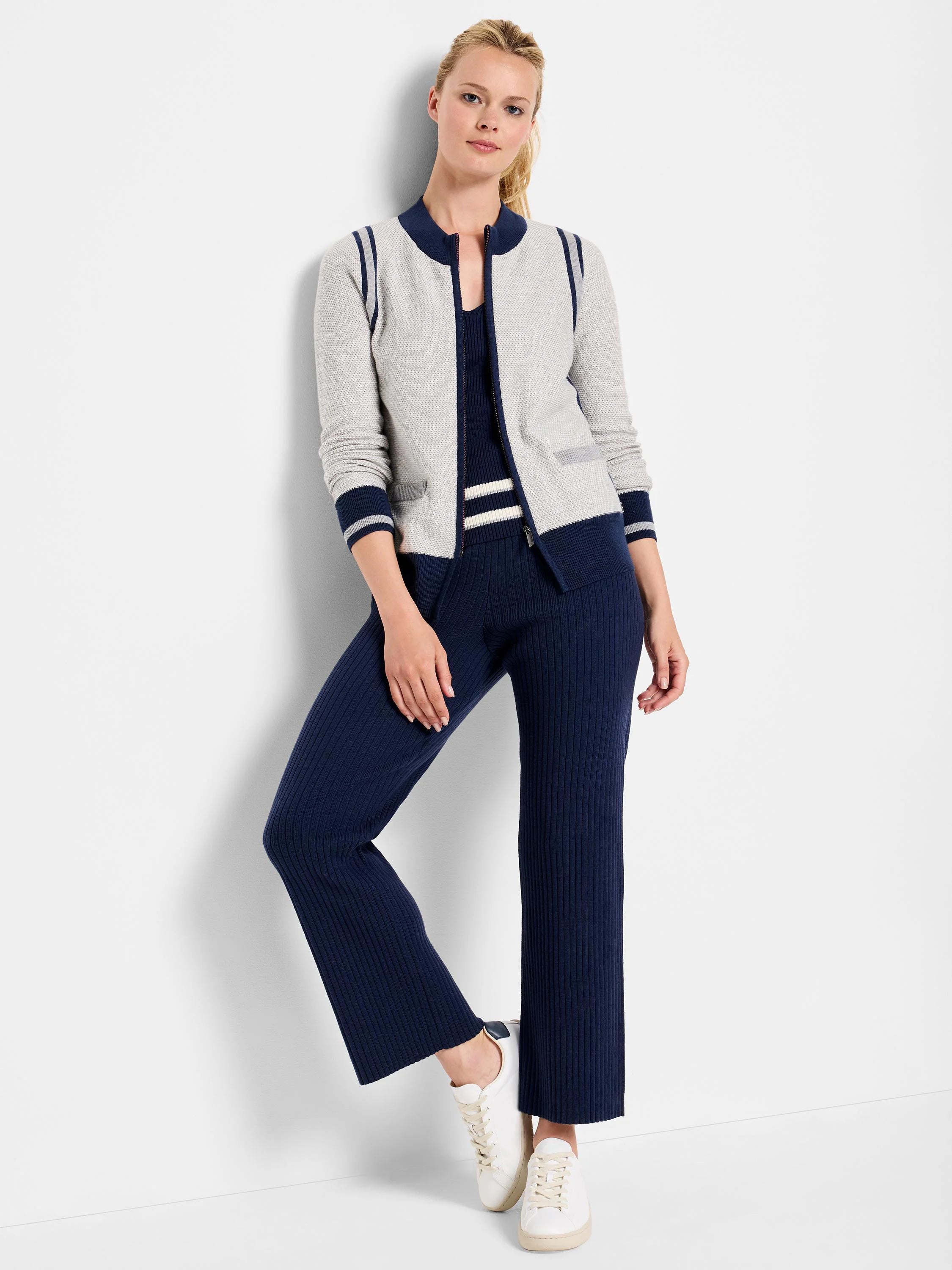Light gray zip-front cardigan with navy blue and white stripes on the collar and cuffs. The model also wears navy blue...