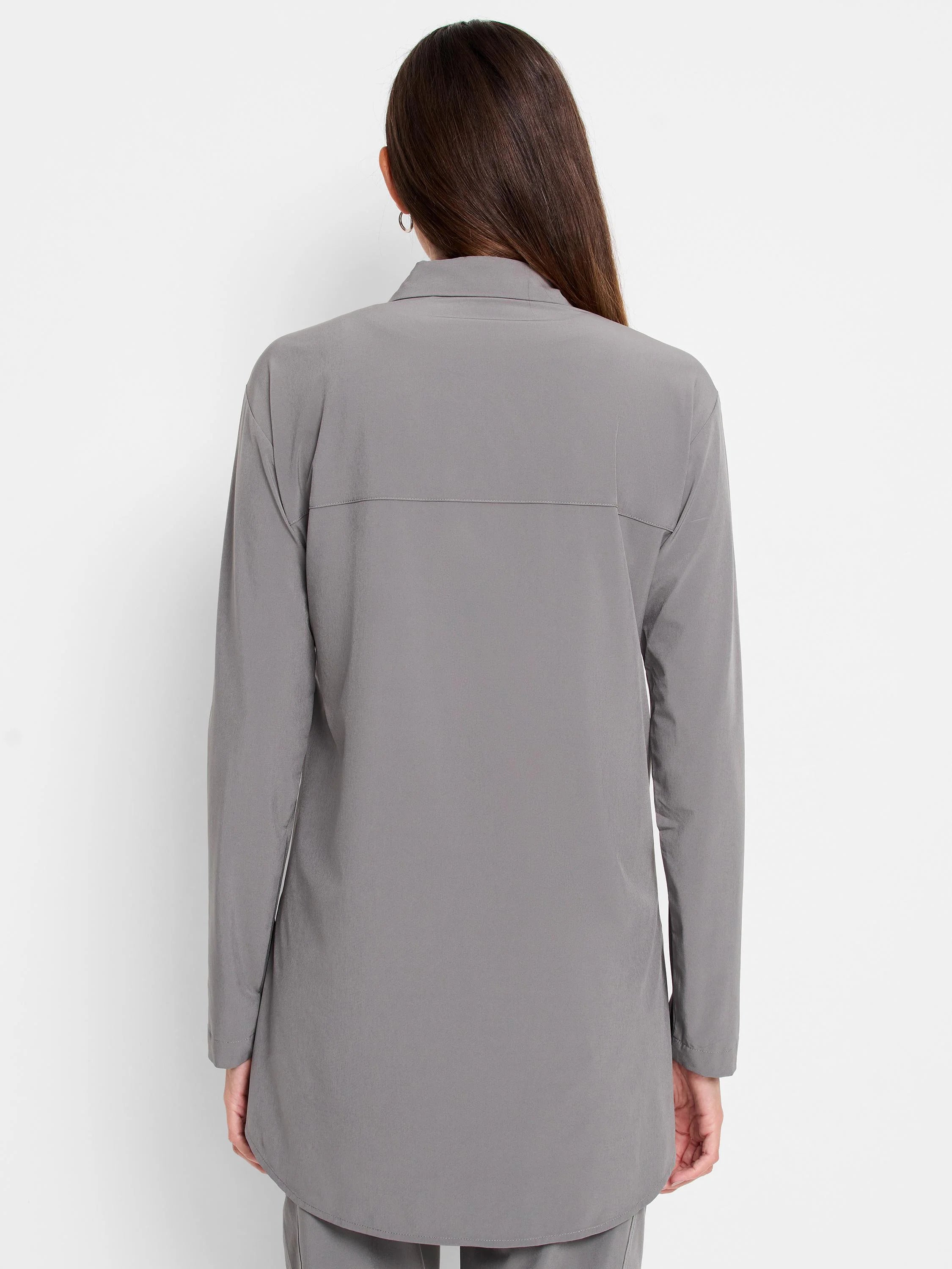 Back view of a woman wearing a grey, long-sleeved collared shirt with a relaxed fit and back yoke.