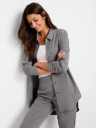 Model wears a relaxed-fit grey collared tech stretch shirt, unbuttoned, over a white tank top.