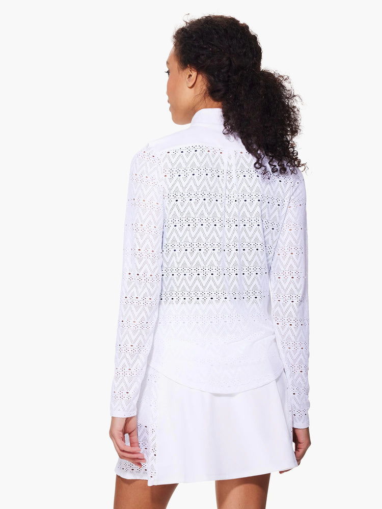 White long-sleeve jacket with repeating chevron eyelet pattern. Paired with a white A-line mini skirt.
