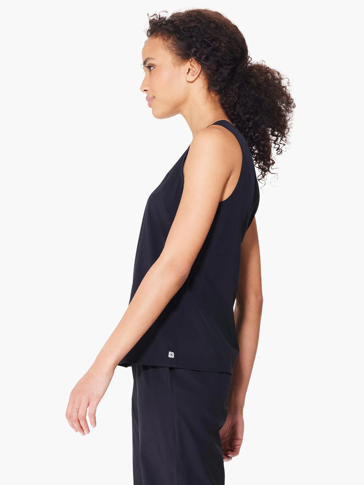 Black sleeveless top, seamed detail, small logo. Side profile view on model.