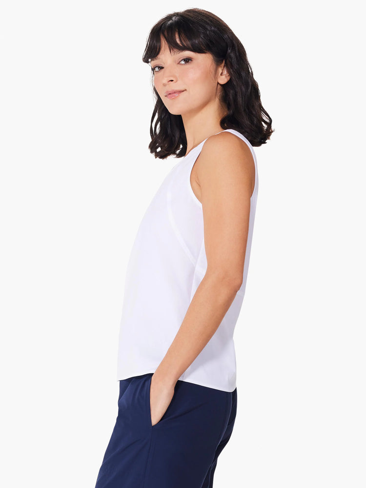 White sleeveless tank top, seamed detail. Model wears navy pants.