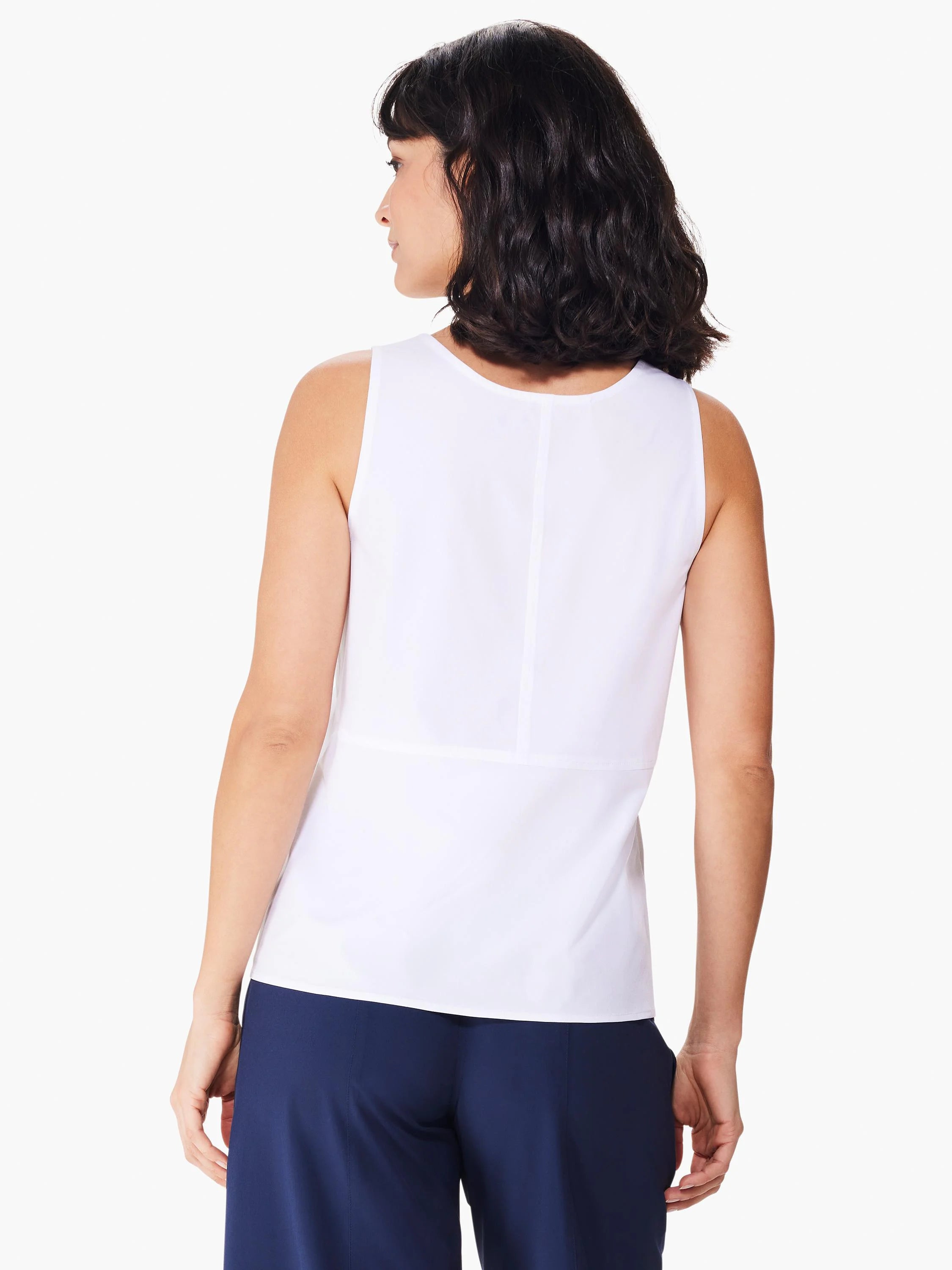 White sleeveless top, seamed down the back. Model shown wearing navy blue pants.