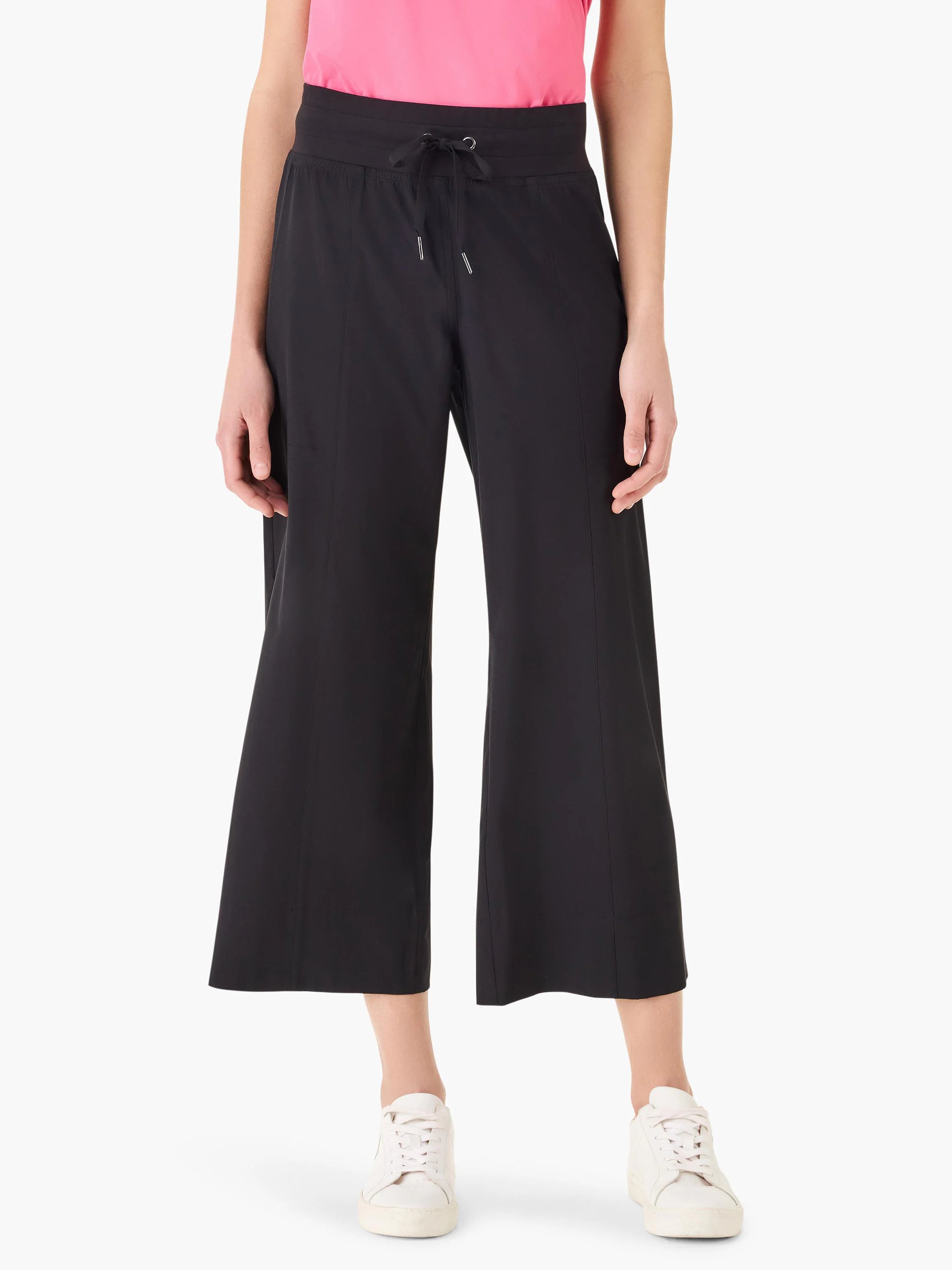 Black wide-leg cropped pants with elastic waistband and drawstring. Model wears white sneakers.