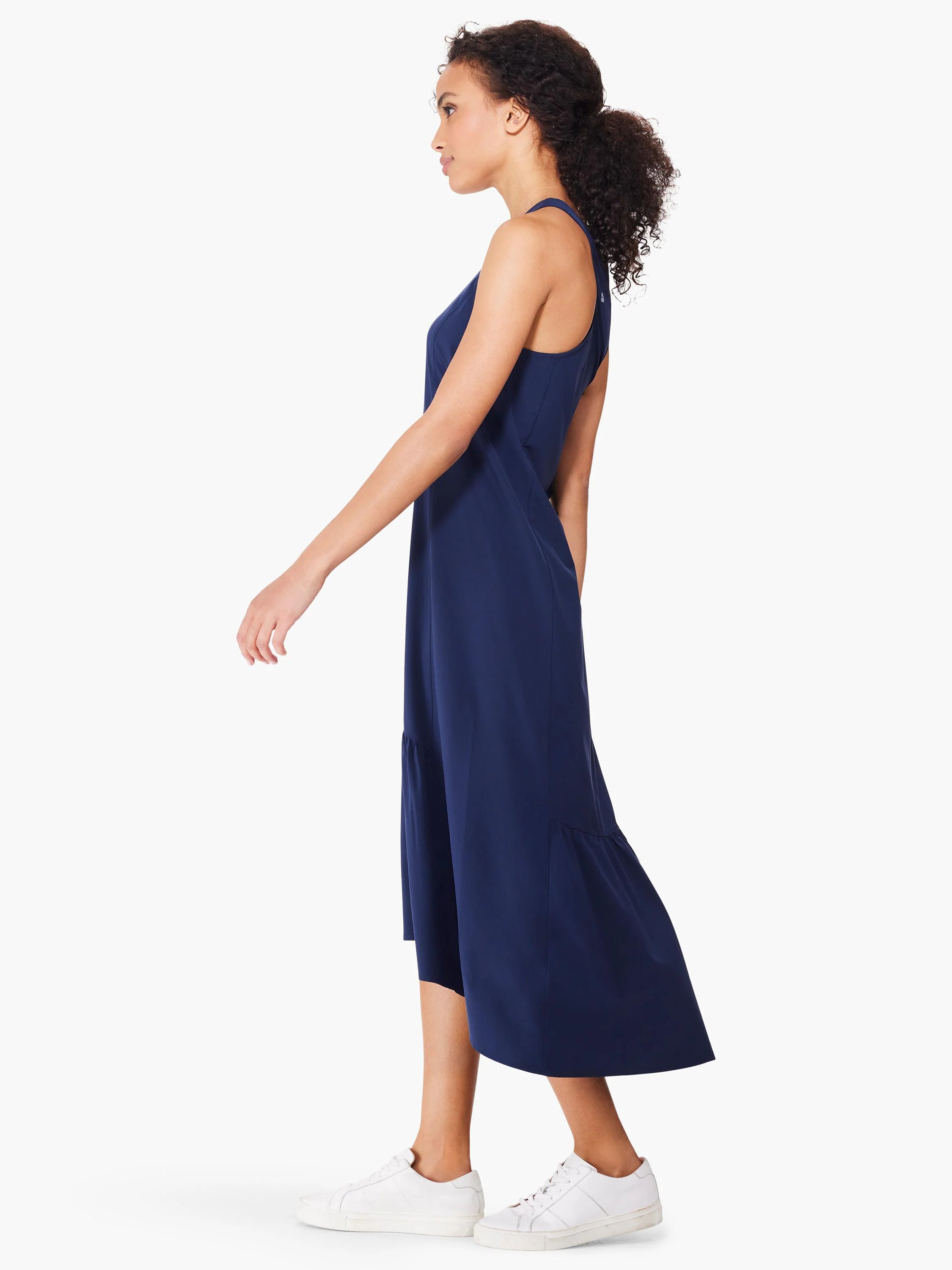 Navy blue sleeveless maxi dress; high-low hemline; shown on model wearing white sneakers.