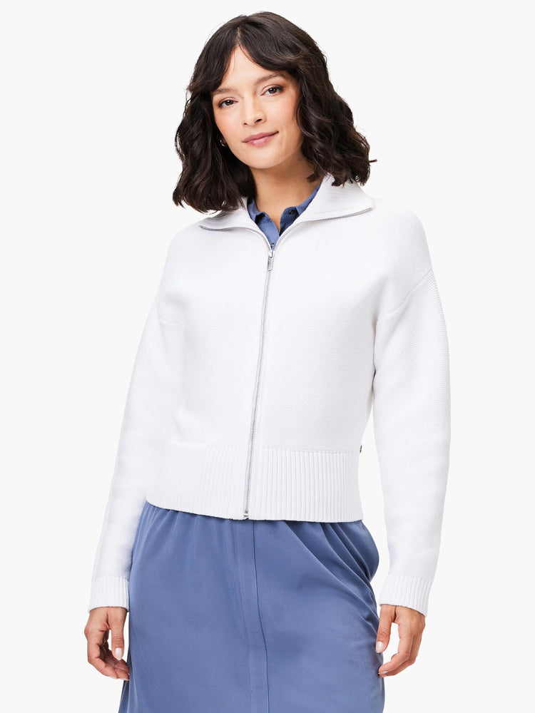 Off-white zip-front sweater jacket with ribbed cuffs and hem. The model is wearing a blue skirt.
