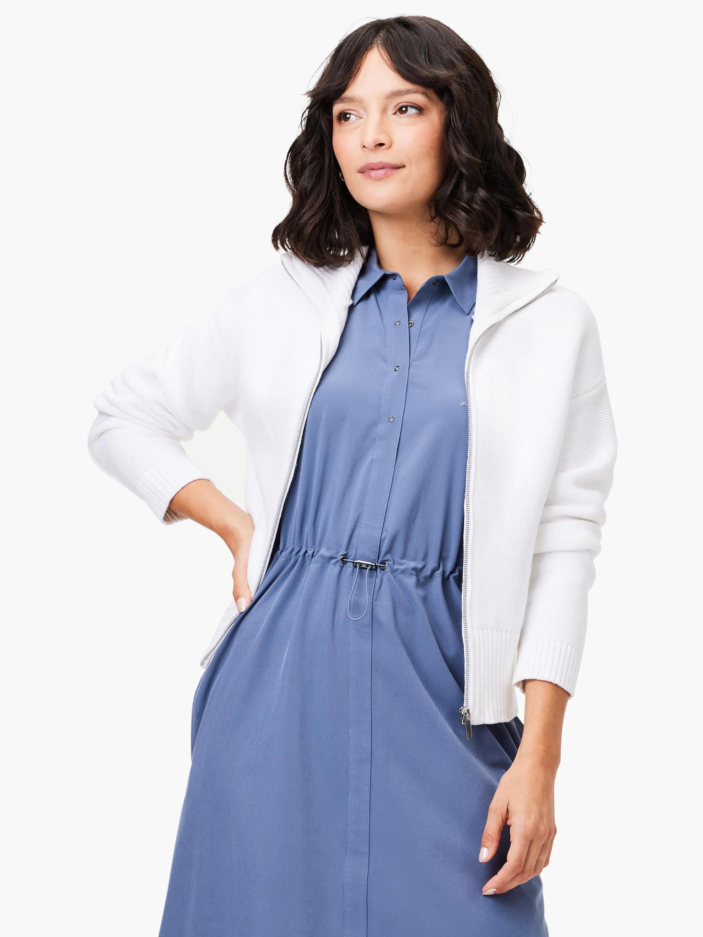 Off-white zip-front sweater jacket. Ribbed cuffs and hem. Model wears it over a blue dress.