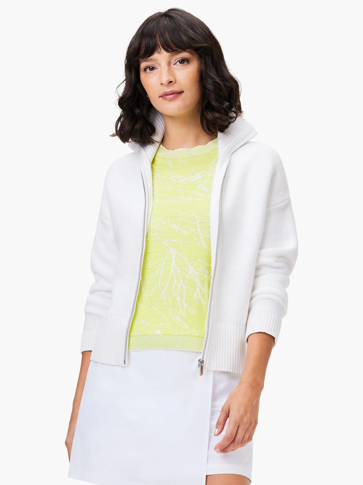 White zip-up sweater, ribbed texture. Features a light lime green, textured top underneath.