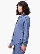 Muted blue collared, long-sleeved shirt with a relaxed fit, button-down front, high-low hem, and side slits.