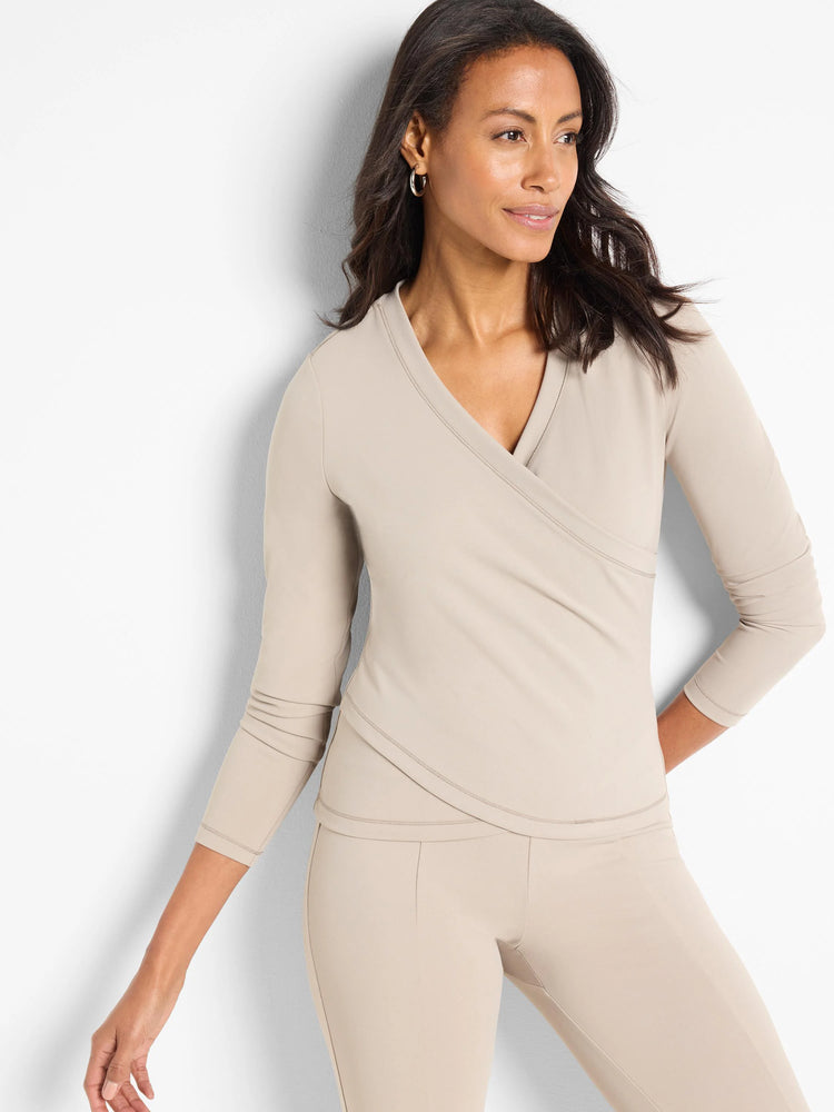 Beige, long-sleeved wrap top with V-neckline. Three-quarter sleeves. Matching beige pants shown.