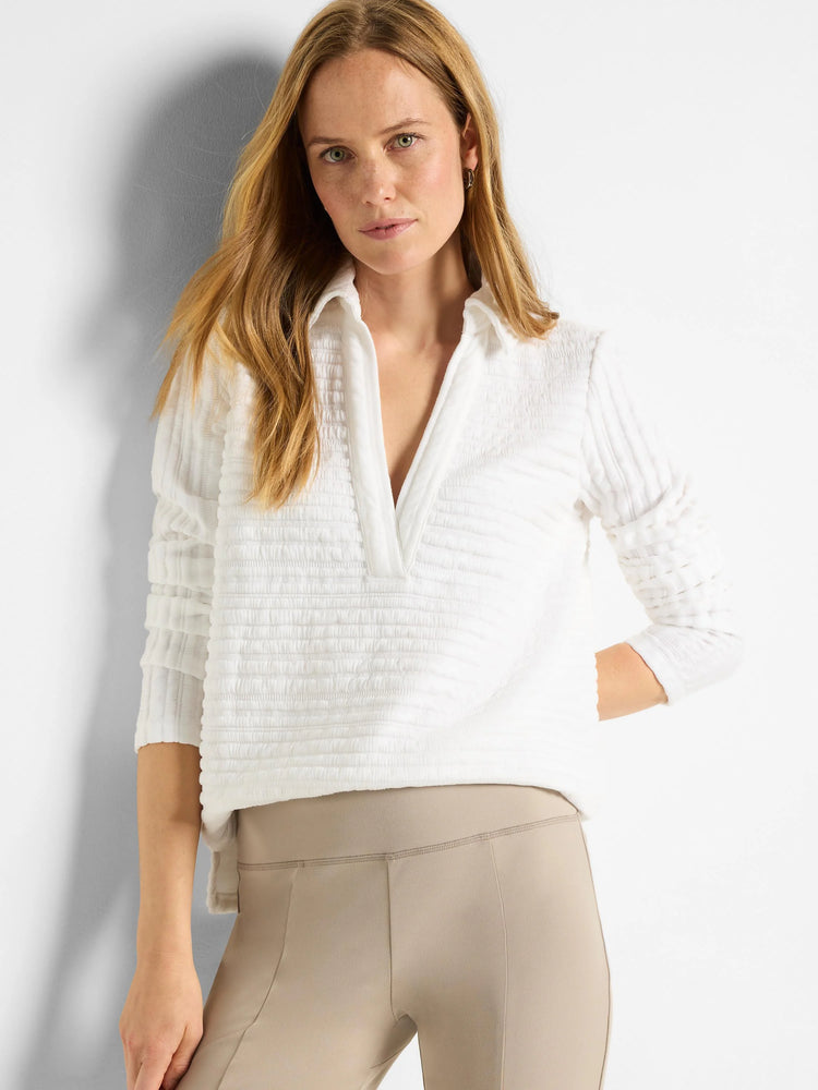 White textured polo shirt with a subtle stripe pattern and long sleeves. Features a v-neck collar.