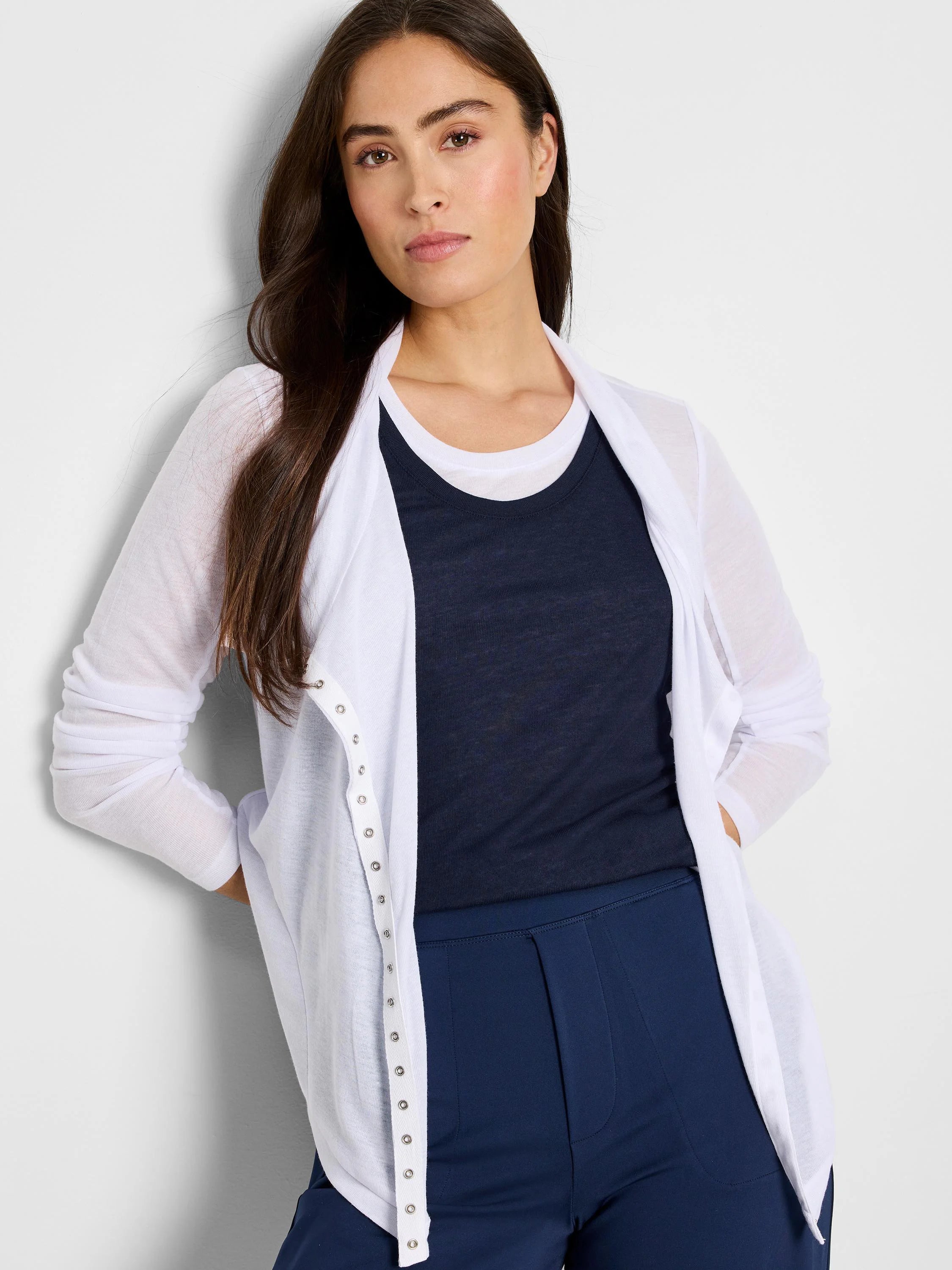 White gauzy cardigan with long sleeves and silver snap closures down the front. The model is wearing it over a dark navy...