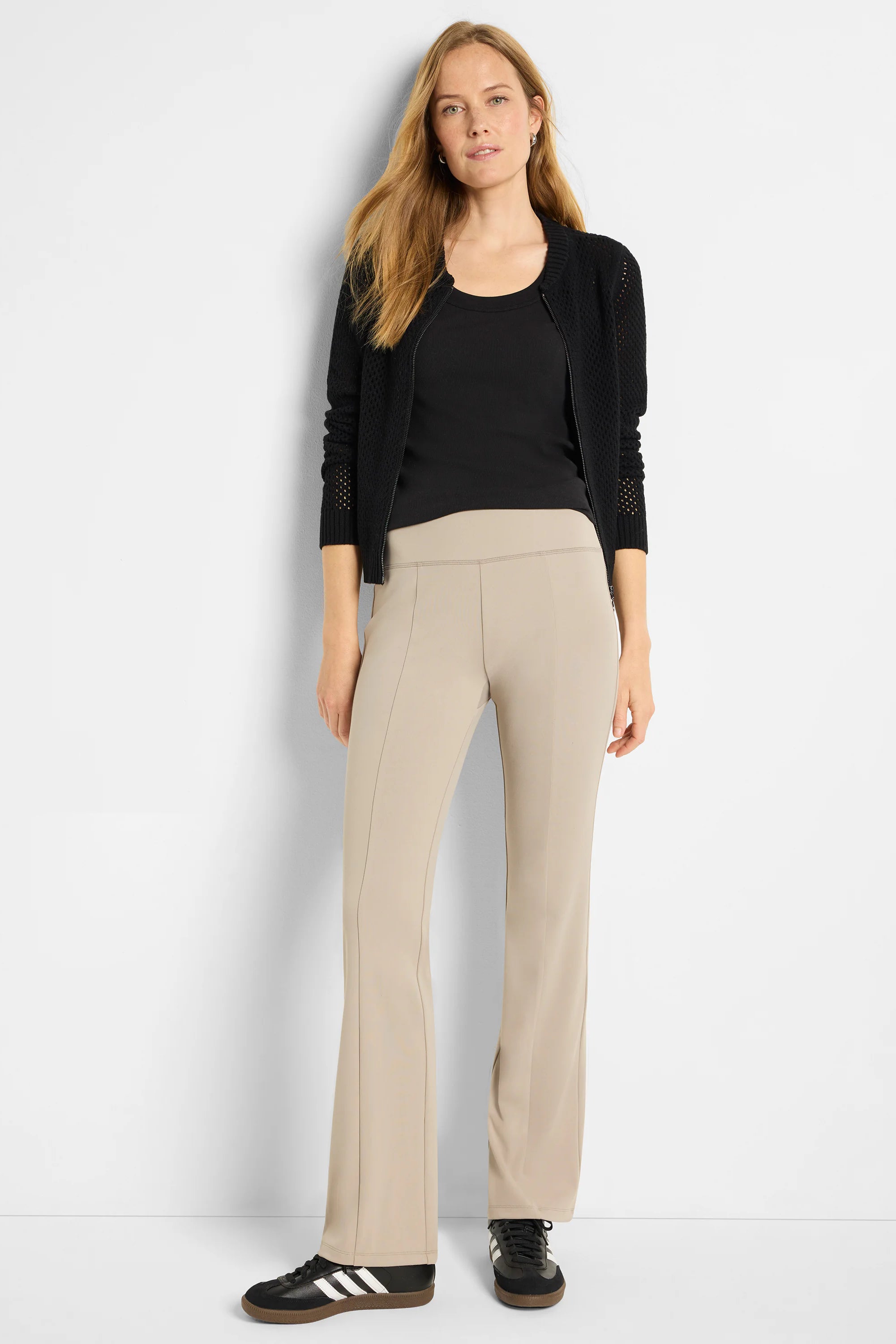 Black mesh zip-front cardigan over black top; beige pants.
